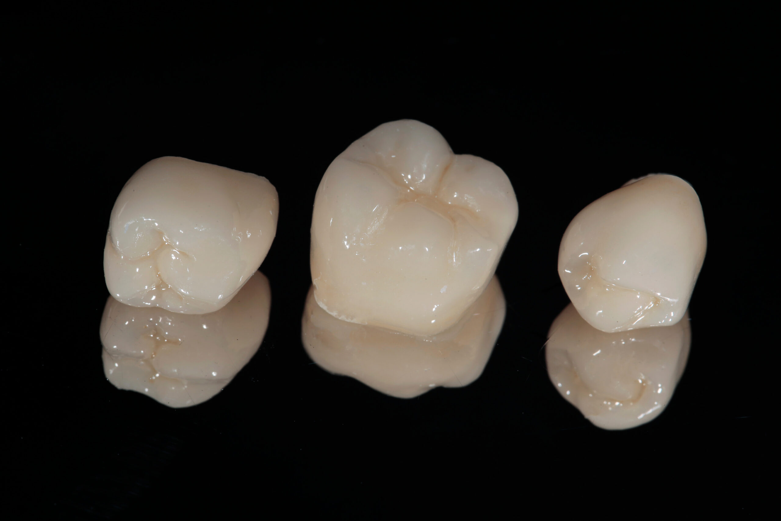 Different sized ceramic dental crowns laying on side by side